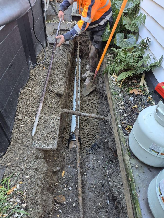 Smart Contracting drainlayer laying new pipe in a bedded trench on a Christchurch repair job