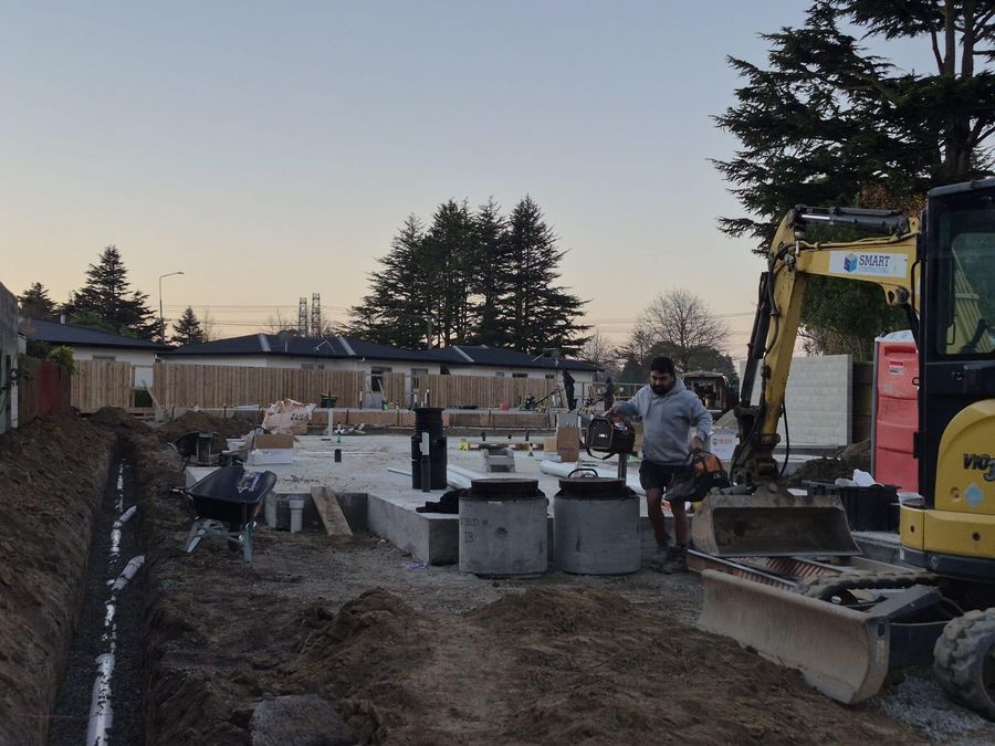 Smart Contracting excavator and new drainage chambers on a Christchurch new build at dusk