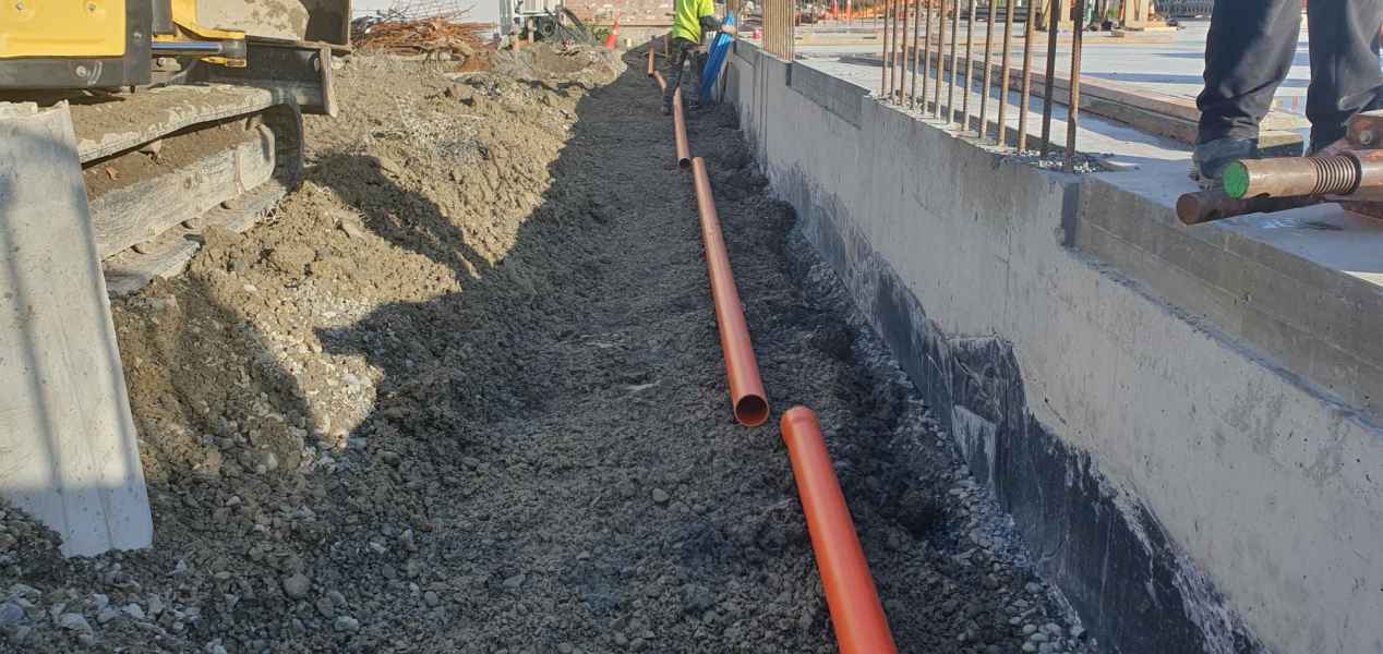Stormwater pipe laid against a commercial foundation wall in Christchurch