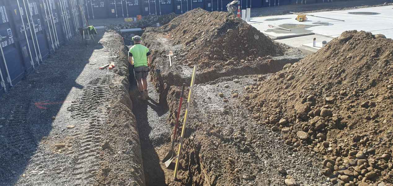Drainlayer working a long commercial drainage trench in Rolleston