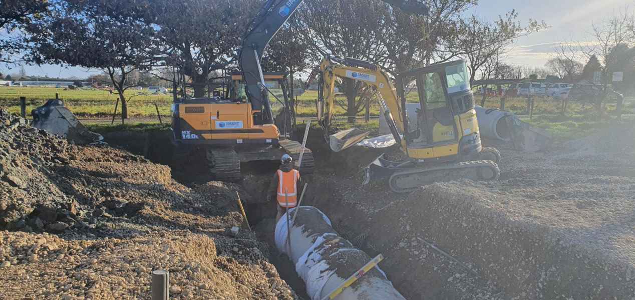 Two excavators laying large diameter civil drainage pipe in Canterbury